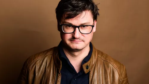 Sebastian Gießmann in Lederjacke vor einem braunen Hintergrund
