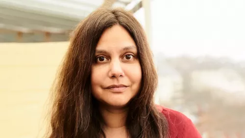 Mithu trägt lange dunkle Haare und ein rotes Tuch um den Oberkörper.