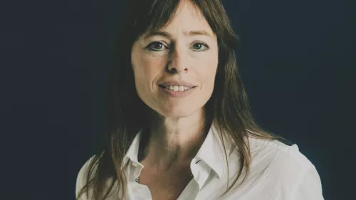 Hedwig Richter hat lange glatte Haare und trägt eine Bluse. Sie schaut in die Kamera und lächelt. Dabei steht sie vor einem dunklen Hintergrund.