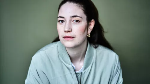 Ein Foto der Sprecherin. Sie trägt die Haare nach hinten zusammengebunden und eine mintgrüne Jacke.