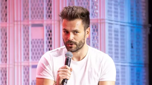 Tilo Jung auf der republica 23, er hält ein Mikrofon in der Hand und trägt ein weißes Shirt. Hinter ihm sind weiße Bäckerkisten als Bühnendeko zu erkennen.
