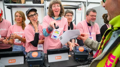Mehrere Voplunteers an der Akkreditierung, eine Person scannt ein Ticket ein.