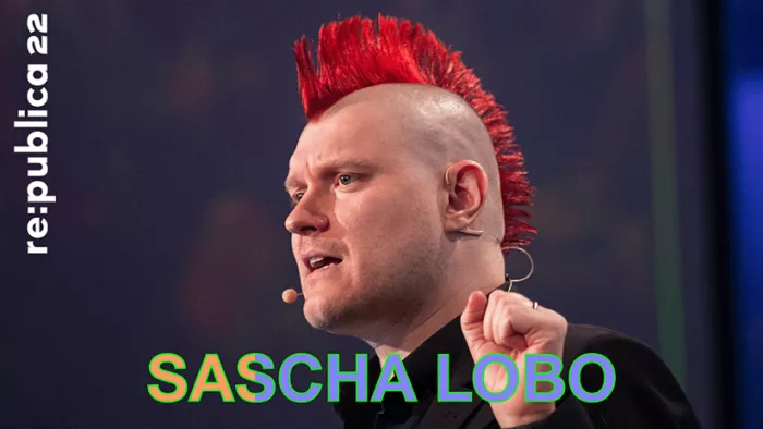 Porträtfoto von Sascha Lobo auf der Bühne der re:publica mit halbhoch erhobener Faust