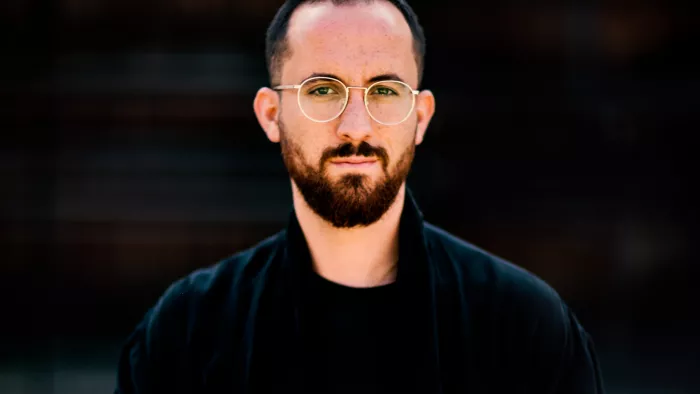 Igor Levit steht in schwarzem Hemd vor einem schwarzen Hintergrund.