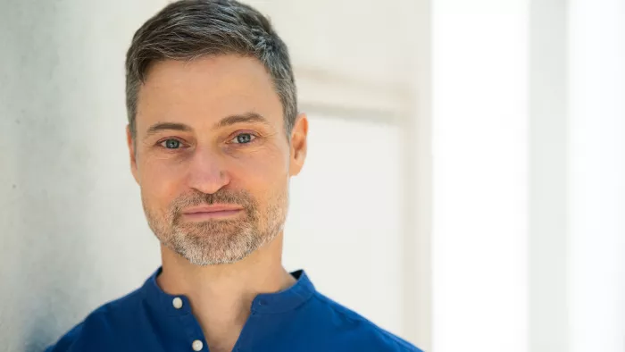 Meron Mendel in einem blauen Shirt vor hellem Hintergrund.