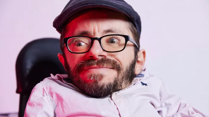 Raul trägt kurze Haare, eine dunkle Schiebermütze und ein helles Hemd.