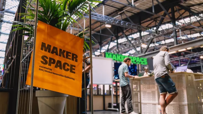 Ein Schild für den Maker Space auf der re:publica. Im Hintergrund sind Menschen zu erkennen.