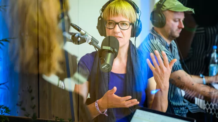 Eva Wolfangel als Gast bei der Aufnahme einer re:publicast-Folge. Sie trägt einen Kopfhörer und spricht in ein Mikrofon.