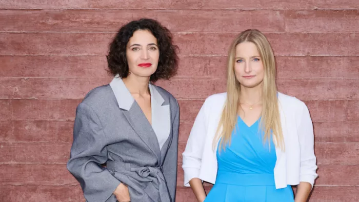 Foto von Josephine Ballon und Anna-Lena von Hodenberg. Sie beide tragen Blazer, offene Haare und stehen vor einer Wand