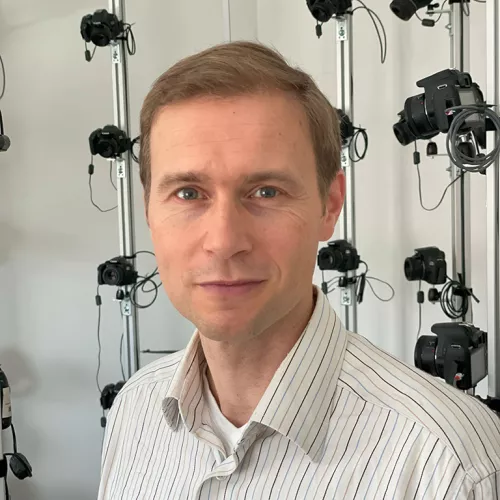 Portrait von Björn Stockleben, Brustbild mit einem Gerüst mit vielen Fotokameras im Hintergrund
