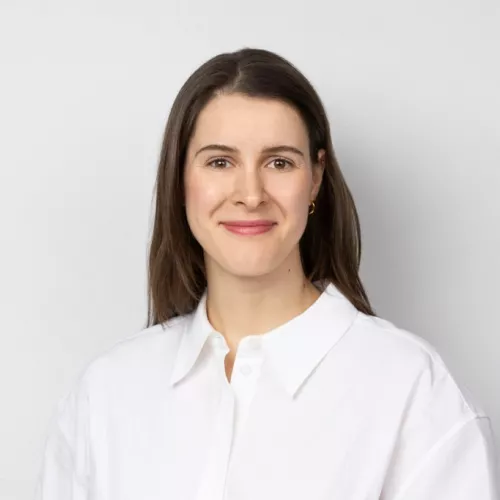 Photo of woman with dark hair in a white shirt on a grey background
