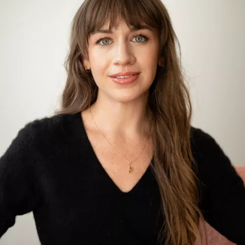 A colour headshot of Brandi Geurkink, a white woman with long brown hair wearing a black v-neck shirt.