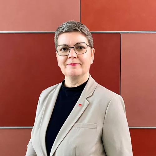 Porträt einer Person im Business-Outfit vor einer roten Wand