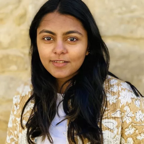 headshot of ramya chandrasekhar, black hair, yellow printed jacket, brown skin
