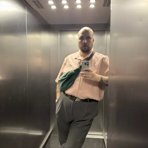 Mann lehnt im Fahrstuhl und macht ein Selfie