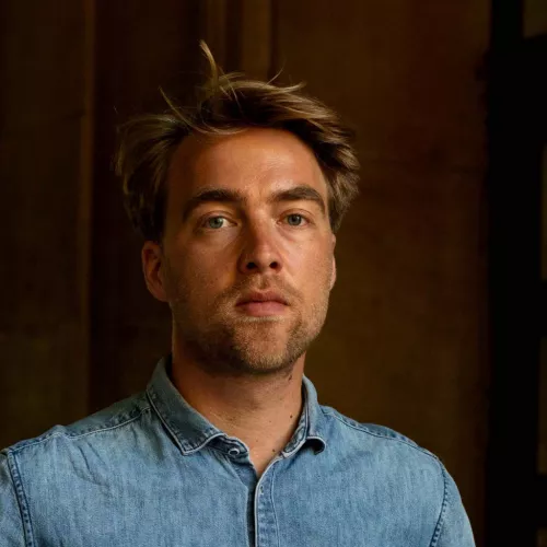 Headshot of a blonde haired man looking straight into the camera