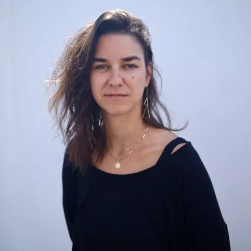 Frau mit braunen Haaren vor einem hellen Hintergrund