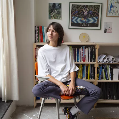 A portrait of Eva sitting on an orange chair