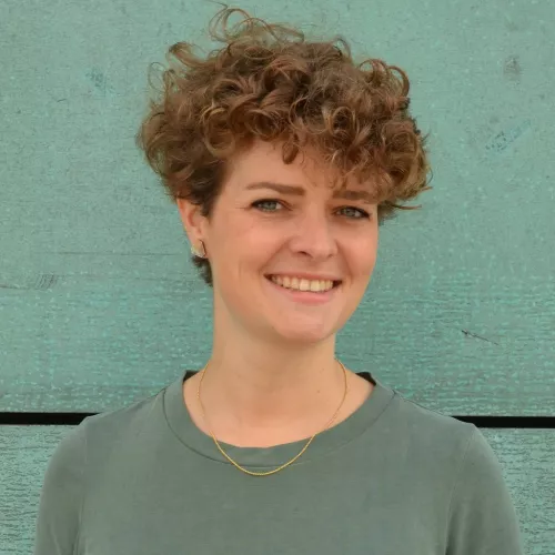 Die Journalistin Pia Uffelmann steht vor einem grünen Hintergrund