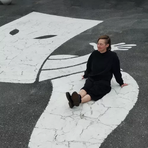 Frauke Boggasch sitzt in Sakaiminato (Japan) auf einem großen weißen Geist, der auf den Asphalt gemalt ist.