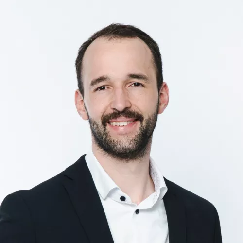 Foto einer Person mit Anzug vor weißem Hintergrund. 