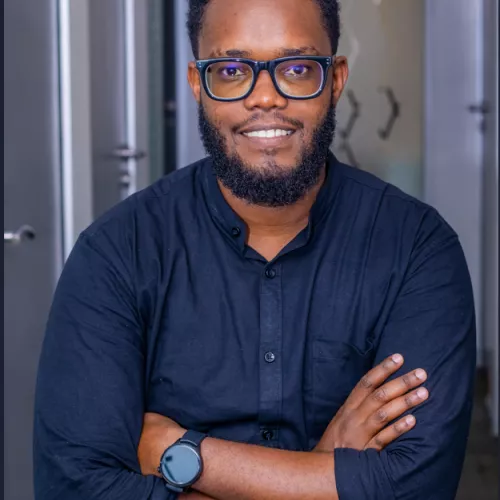 A smiling person wearing glasses and a black shirt, looking professional and confident.
