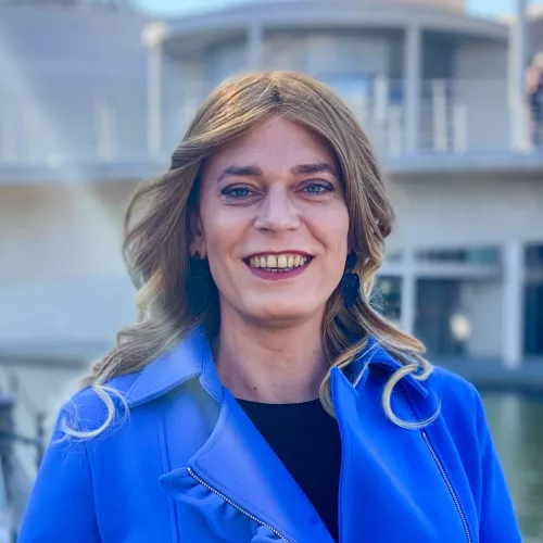 Tessa Ganserer trägt in einem leuchtend blauen Mantel und lächelt