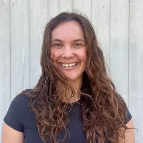 Porträtfoto einer lächelnden, jungen Frau mit langen braunen Haaren
