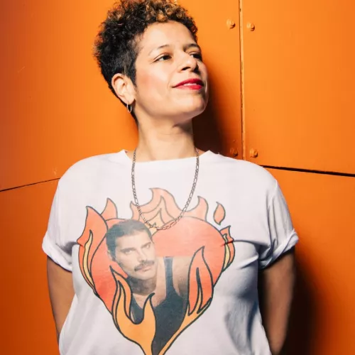 Yasmin Ortega vor orangenem Hintergrund mit Freddie Mercury T-Shirt