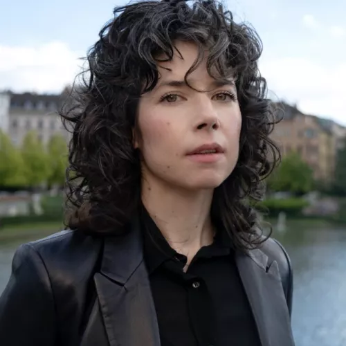 Eine Frau in Lederjacke vor einem Fluss.