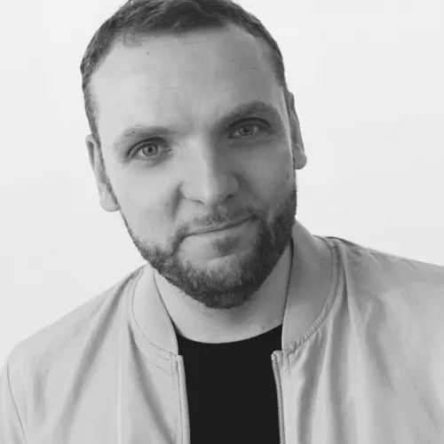 Ein schwarz-weißes Portrait von Christian Richter. Er trägt kurze dunkelbraune Haare und einen Bart. Er schaut frontal in die Kamera.