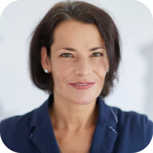 Porträtfoto von Judit Hercegfalvi. Sie trägt mittellange dunkelbraune Haare und einen dunkelblauen Blazer.