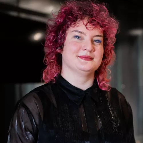 Person mit schwarzer Bluse und rötlichen Haaren