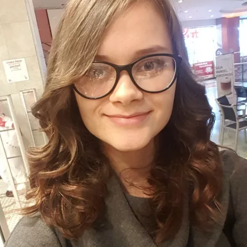 Eine Frau mit langen dunklen Haaren und Brille.