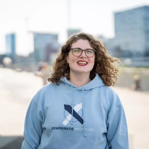 Franziska Hollstein fröhlich in einem Hoddie ihrer Organisation dem Demokratie-Wegweiser