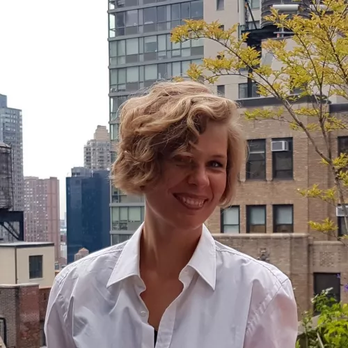 Speaker smiling in front of city background.